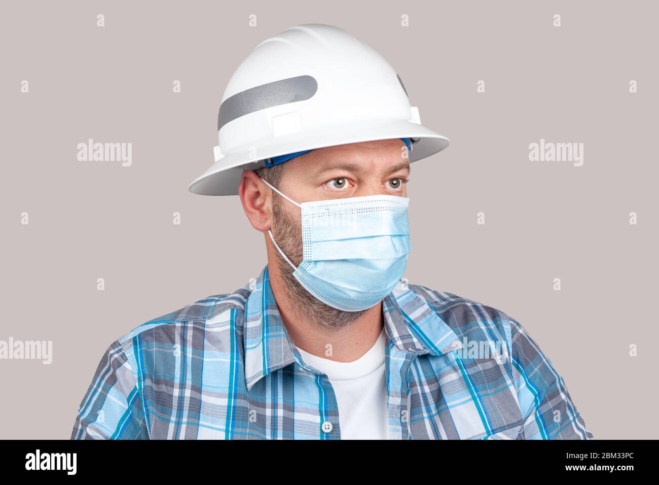 Ingenieur oder Bauarbeiter mit Freizeitkleidung und Sicherheit harten Hut trägt chirurgische Gesichtsmaske. Konzept der neuen Sicherheitsmaßnahmen von Unternehmen Stockfoto