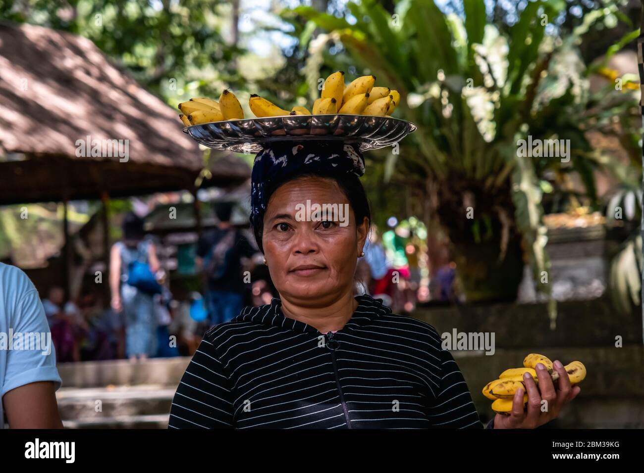 Die balinesische Frau verkauft Bananenfrüchte über ihrem Kopf Stockfoto