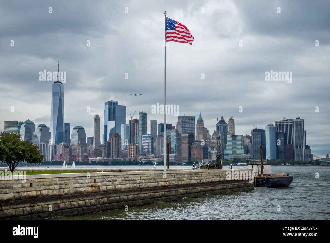 New York Manhattan Skyline von Liberty Island mit amerikanischer Flagge Stockfoto