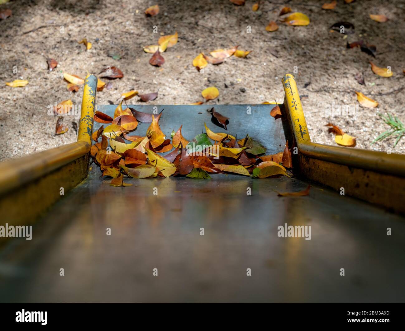 Trockene Blätter an der Basis einer Metallrutsche auf einem Spielplatz, Areal, Rio de Janeiro, Brasilien Stockfoto
