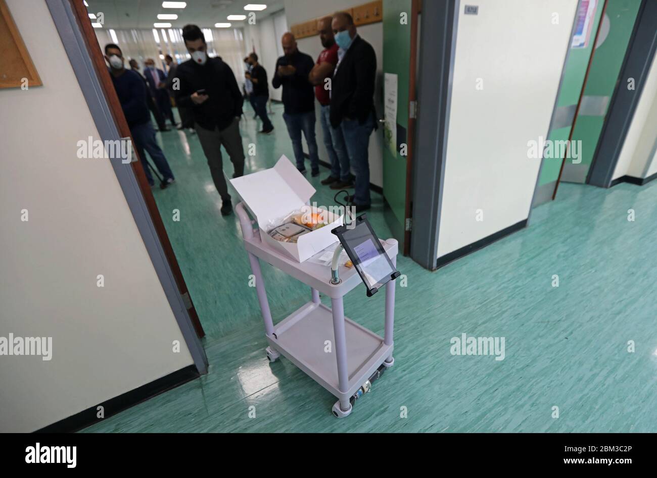 Beirut, Libanon. Mai 2020. Ein Roboterdesigner steuert den Roboterwagen telefonisch im Rafic Hariri University Hospital in Beirut, Libanon, 6. Mai 2020. Die libanesische Universität (LU) hat am Mittwoch einen von Studenten der Universität erfundenen Roboterwagen gestartet, der Ärzten und Krankenschwestern helfen soll, den Kontakt mit COVID-19-Patienten zu verringern und ihr Infektionsrisiko mit dem Virus zu minimieren. Kredit: Bilal Jawich/Xinhua/Alamy Live News Stockfoto