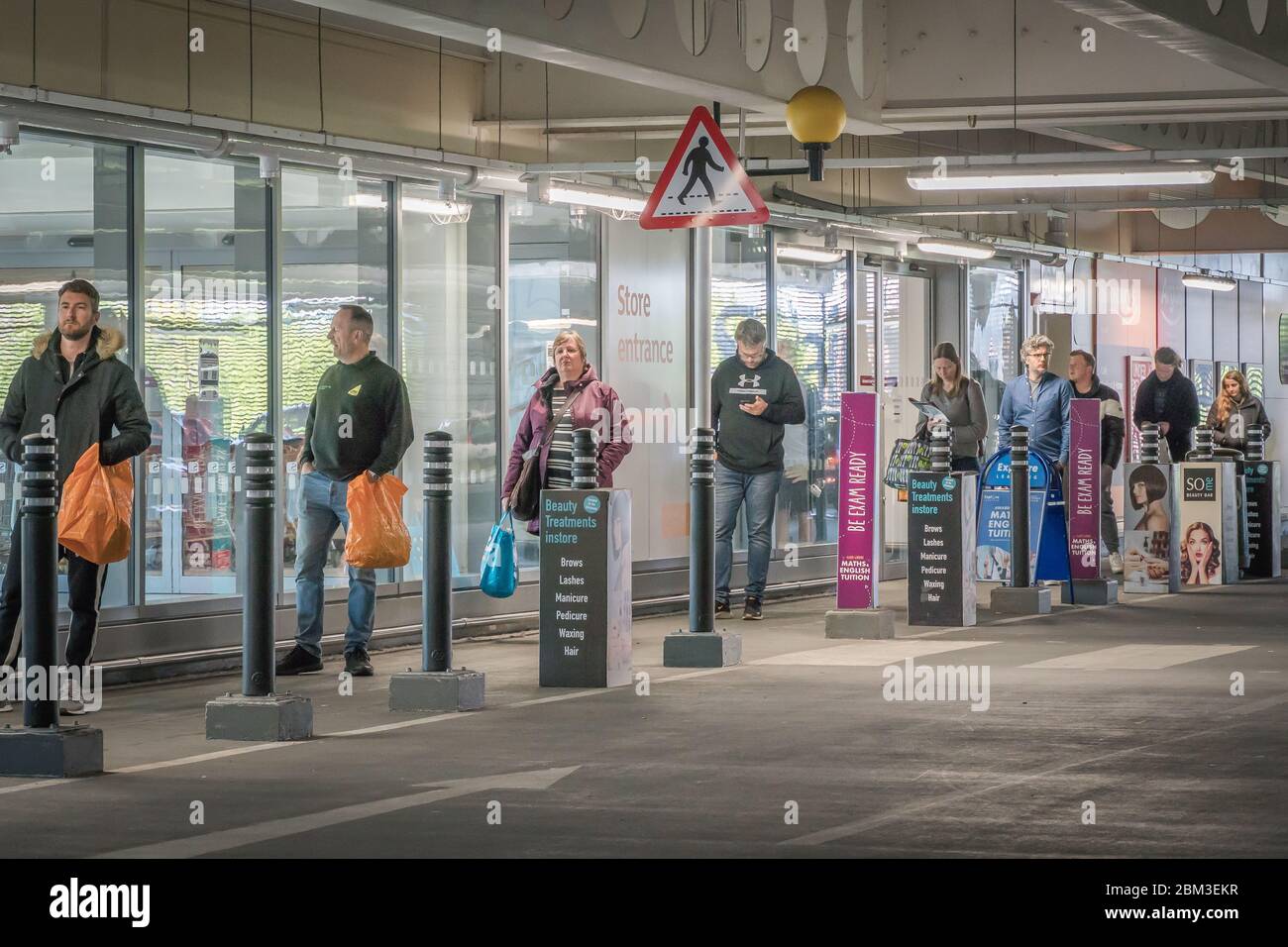 Redhill, Surrey, Großbritannien - 1. Mai 2020 - Einkäufer Schlange vor Sainsbury's Supermarkt, Aufrechterhaltung der sozialen Distanz, um die Verbreitung des Coronovirus zu stoppen Stockfoto