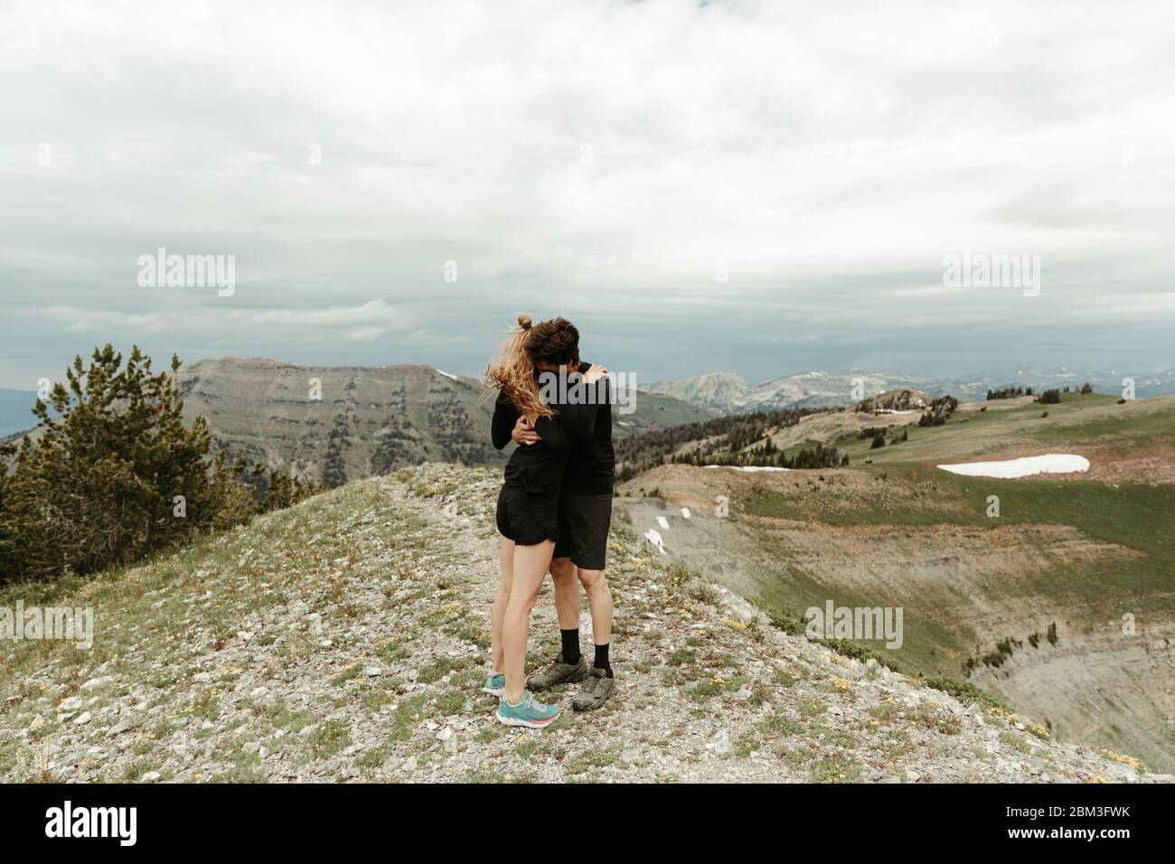 Verlobt Paar in ganz schwarz umarmen Umarmung auf windigen Grat Top in wyoming Stockfoto