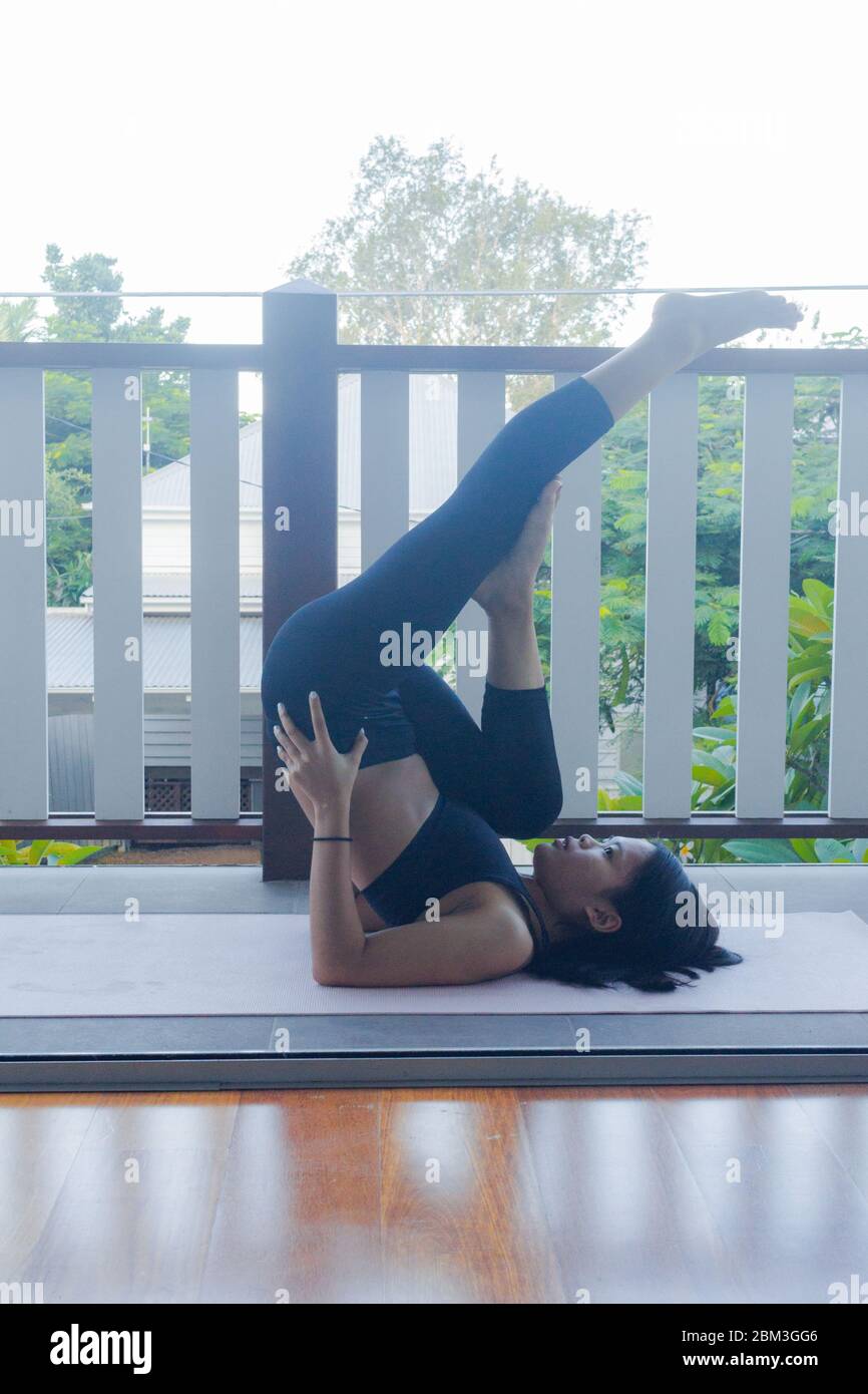 Junge Frau macht Yoga auf Yoga-Matte zu Hause Stockfoto