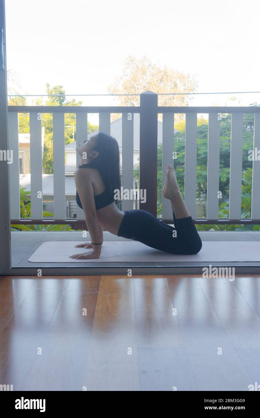 Junge Frau macht Yoga auf Yoga-Matte zu Hause Stockfoto