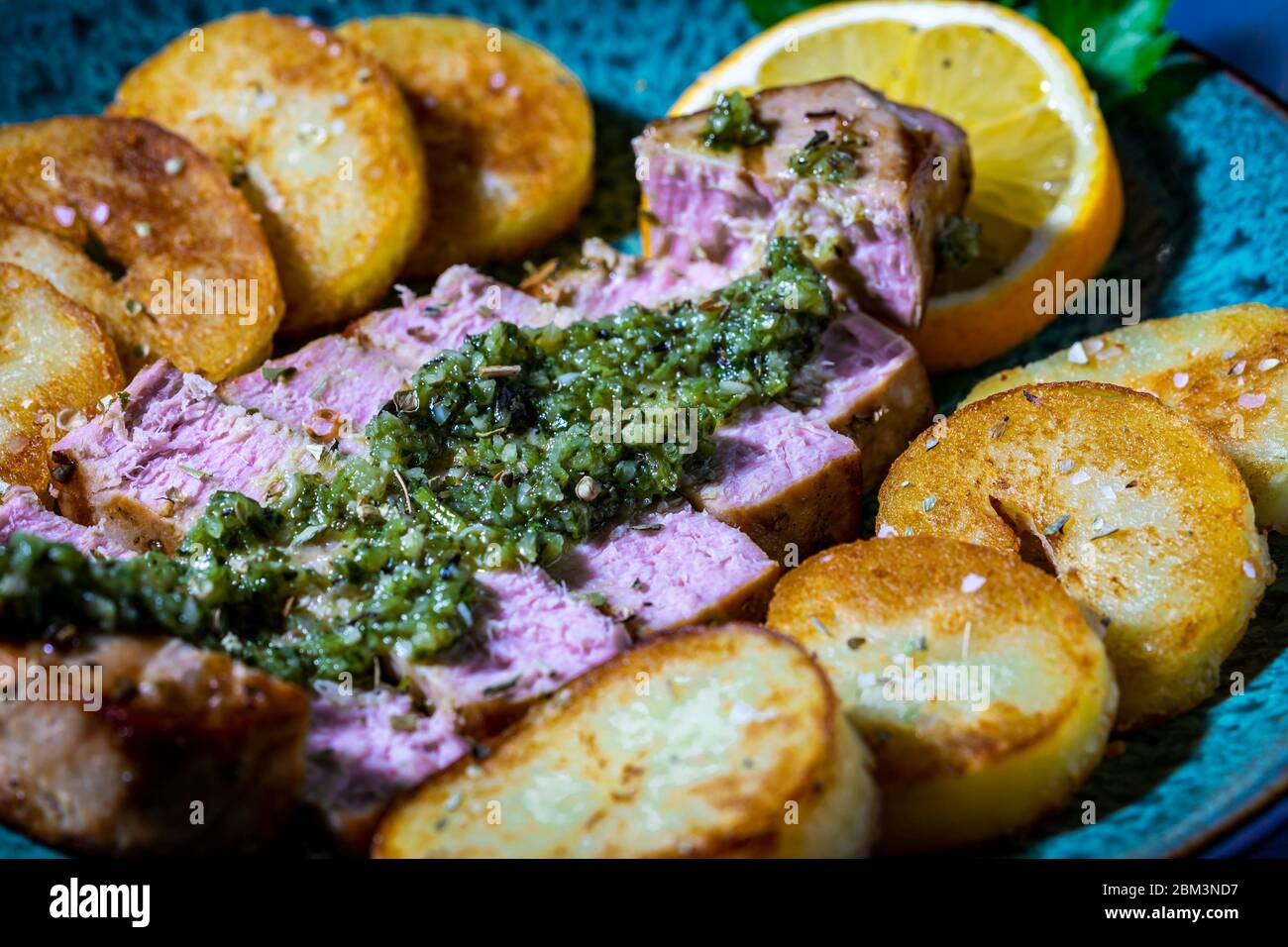 In Scheiben geschnittener Thunfisch mit Chimichurri-Sauce und Bratkartoffeln. Stockfoto