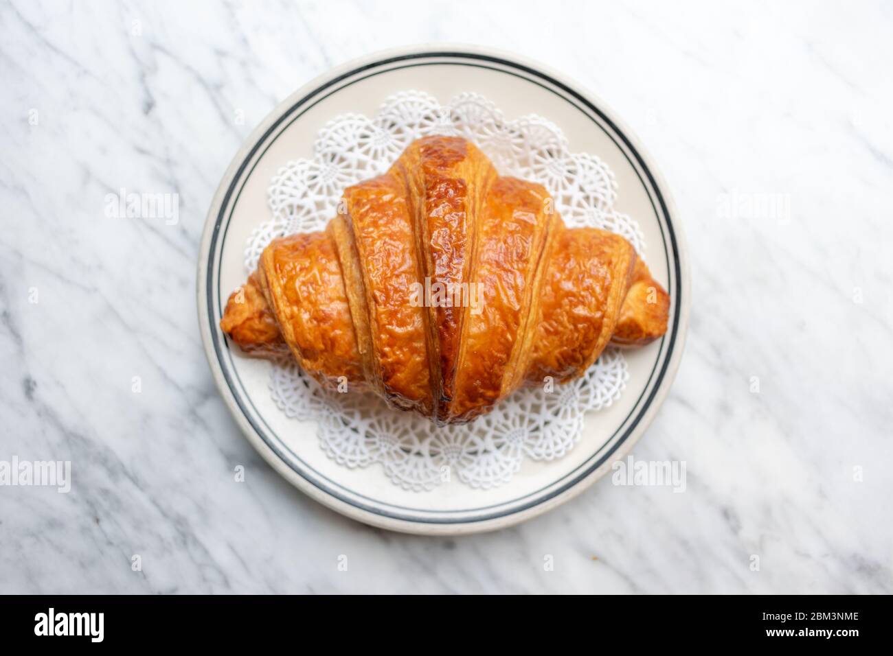 Perfekter Croissant auf einem Teller auf einem Marmor Zähler Stockfoto