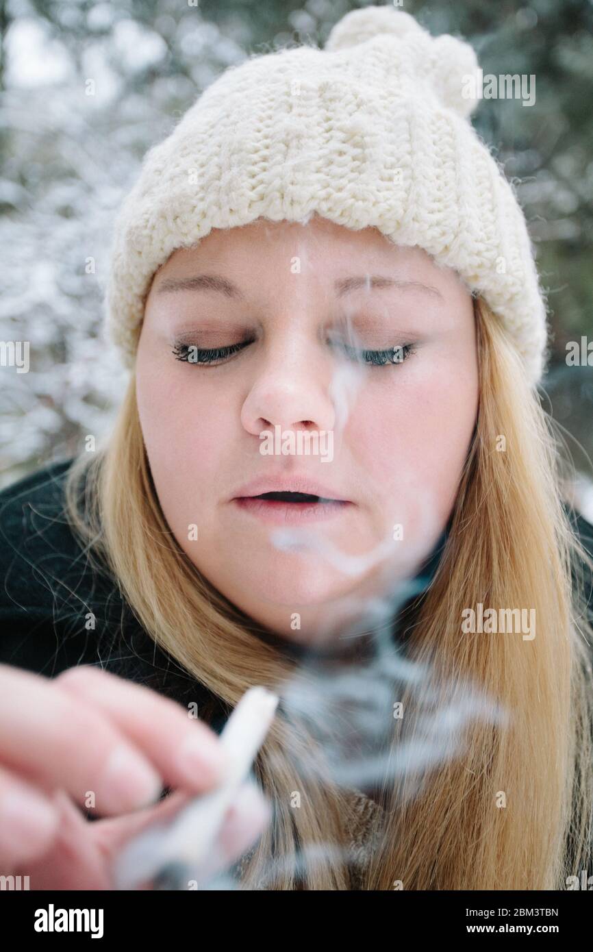 Junge Frau raucht an einem Wintertag eine Marihuana-Zigarette Stockfoto