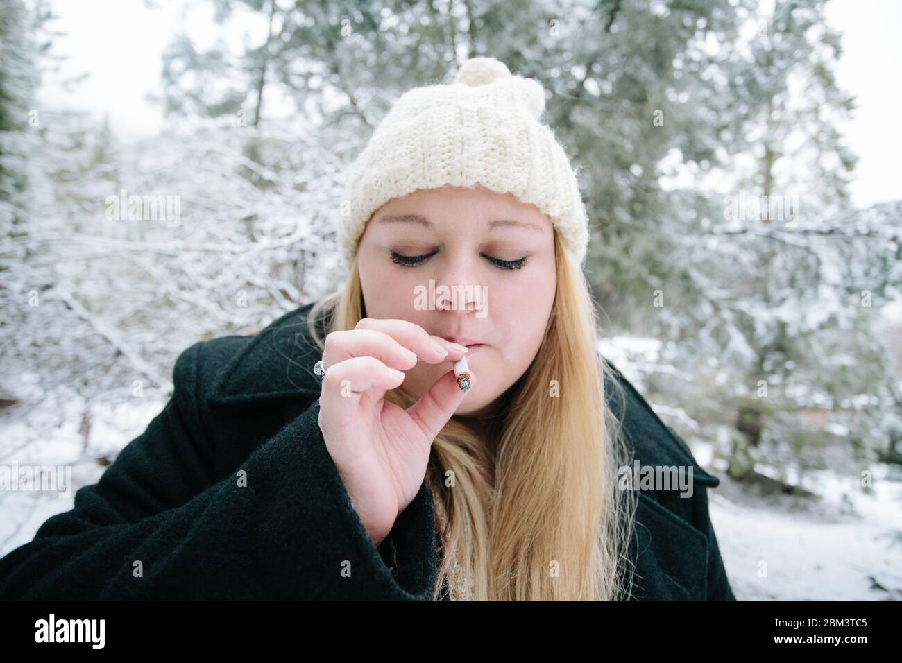 Junge Frau raucht an einem Wintertag eine Marihuana-Zigarette Stockfoto