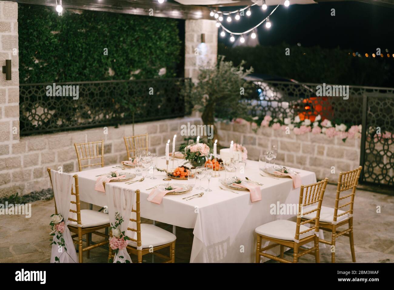 Empfang am Tisch für Hochzeitsessen. Rechteckiger Tisch für sechs Personen mit einer weißen Tischdecke und rosa Servietten. Der goldene Chairofchia ist mit verziert Stockfoto