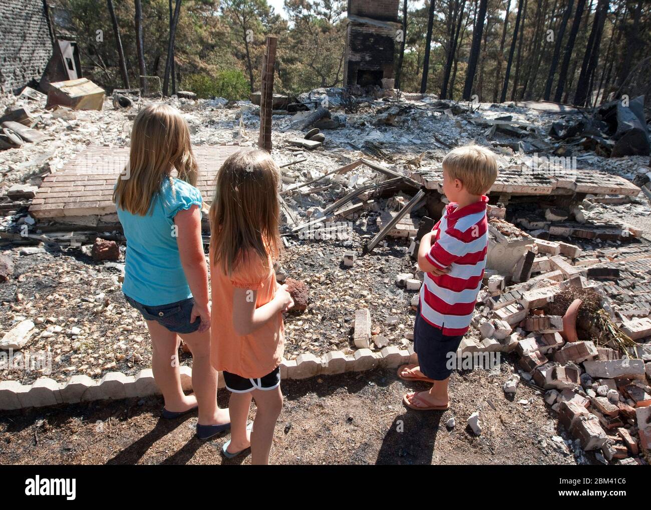 Bastrop County Texas, USA, 9. September 2011: Düstere Kinder betrachten die Überreste eines Hauses, das während massiver Waldbrände zerstört wurde, die Anfang des Monats durch ihre bewaldete Nachbarschaft zogen. ©Marjorie Kamys Cotera/Daemmrich Photography Stockfoto