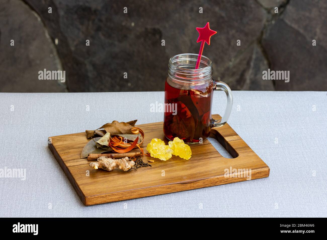 Nahaufnahme eines Einmachglas mit Kräutergetränken und verschiedenen Kräutern auf Steinhintergrund. Stockfoto