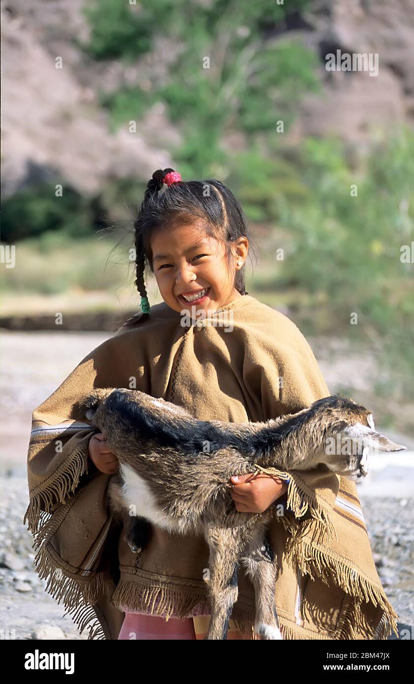 Lächelndes junges indigenes Mädchen mit Ziegenbock in Purmamarca, Jujuy, Argentinien Stockfoto