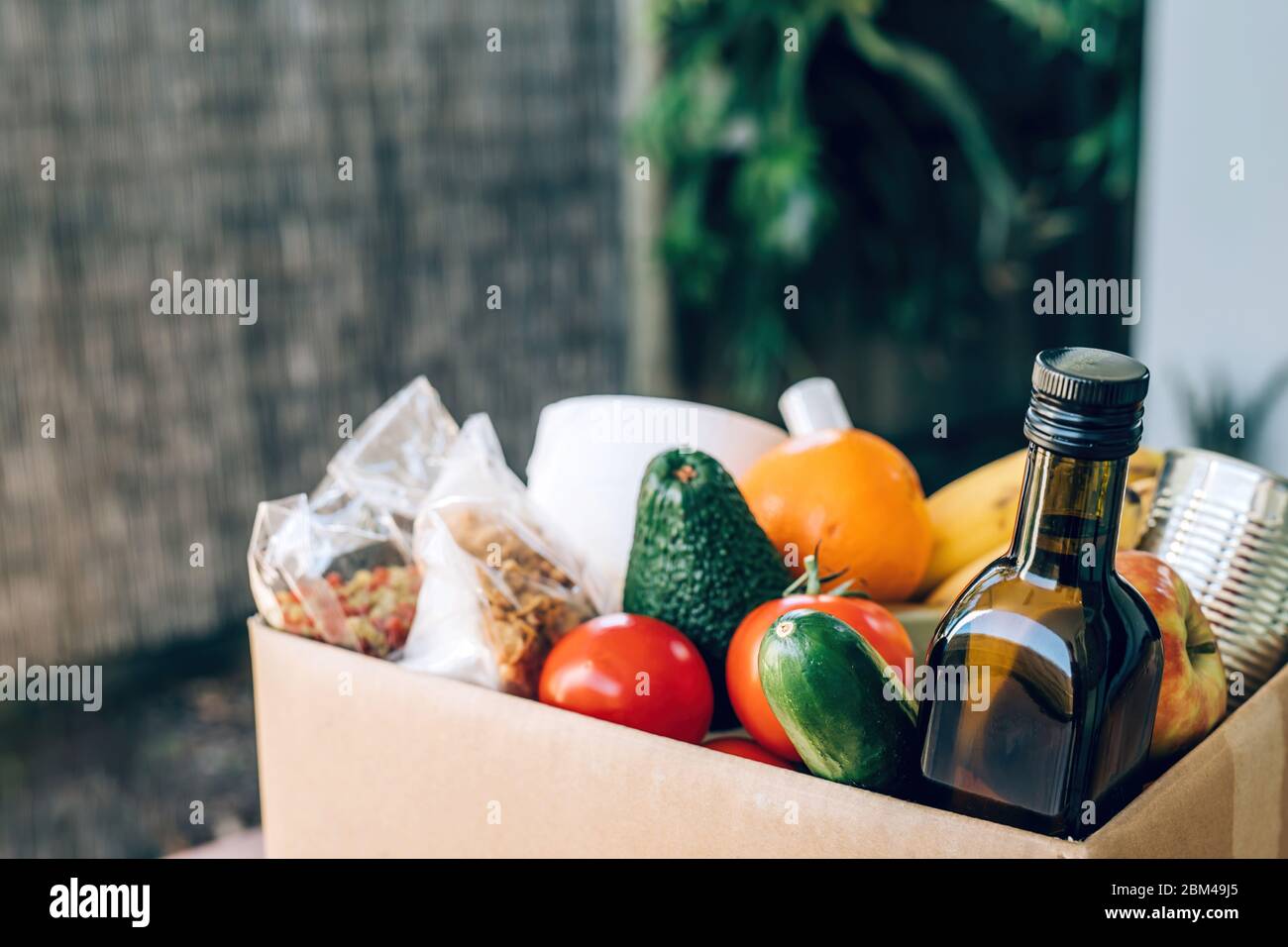 Box mit Lebensmitteln, Toilettenpapier und Handdesinfektionsmittel auf dem Holztisch. Flaches Lay. Covid-19 Ausbruch, Selbstisolierung, Lieferung, Spendenkonzept. Stockfoto