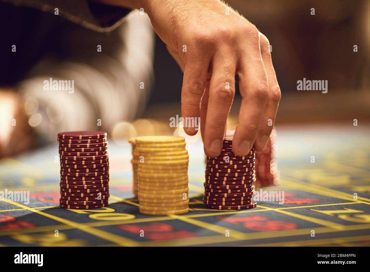 Ein Spieler spielt Roulette in einem Casino. Close-up Hand mit Chips auf dem Roulettetisch. Gambling Casino Spiel Konzept. Stockfoto