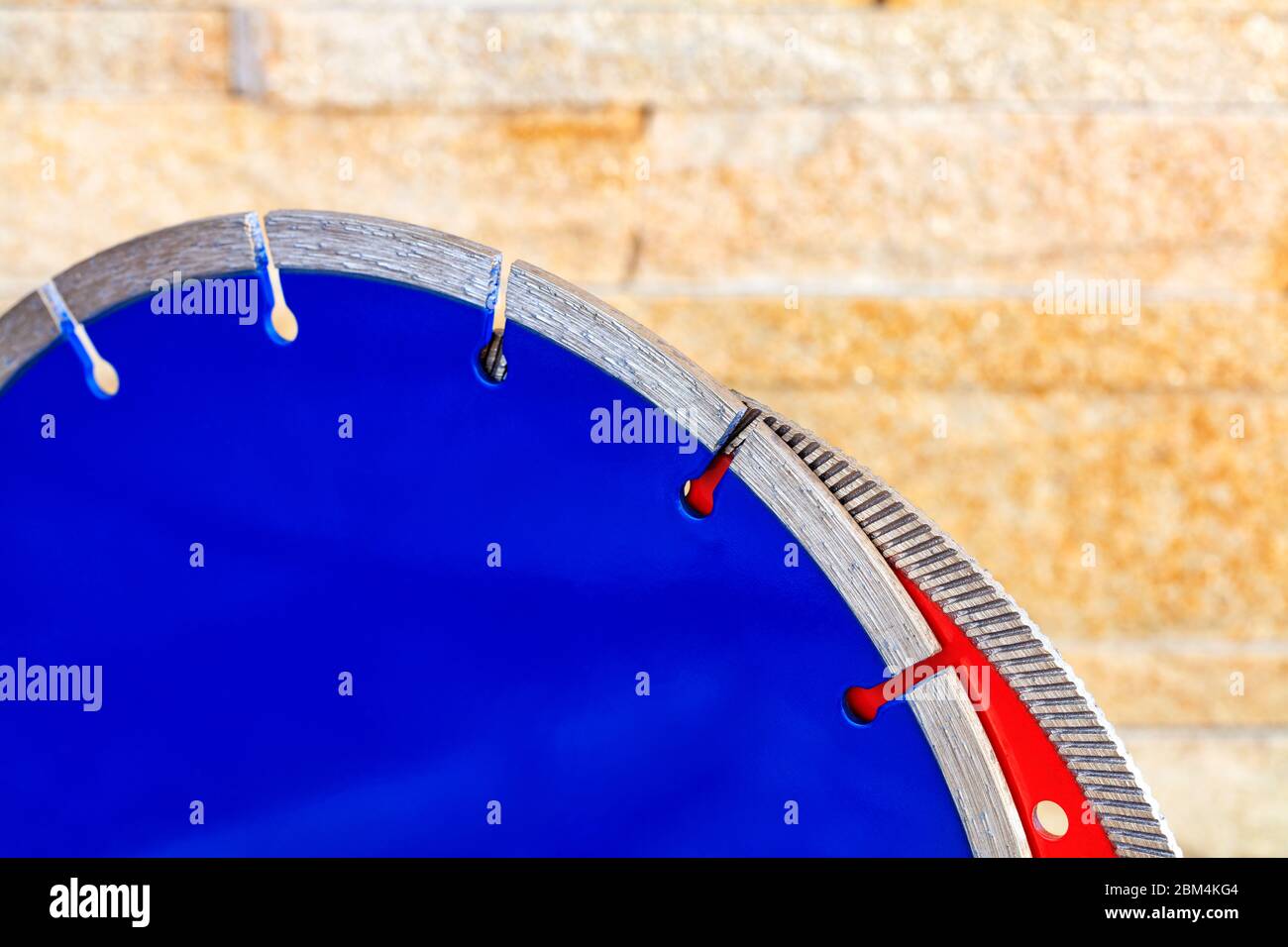 Segmente von Diamant-Schneidescheiben auf Granit und Stahlbeton vor dem Hintergrund einer gelben Sandsteinwand in Unschärfe. Stockfoto
