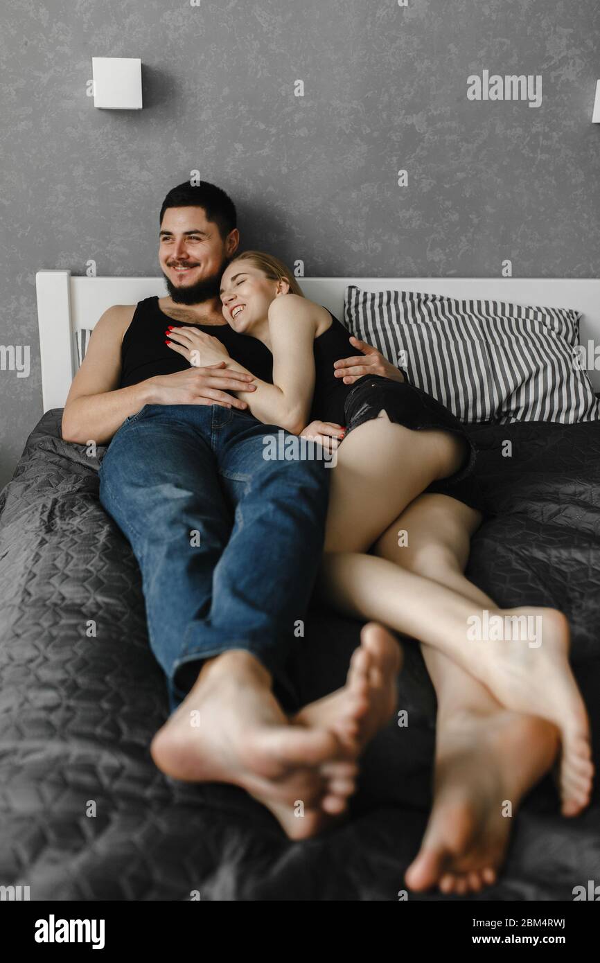 Frau und ihr Mann liegen auf dem Bett und lachen. Bleib zu Hause Stockfoto