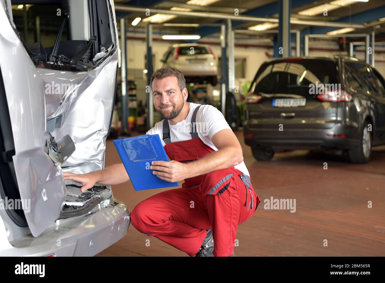 Kfz-Mechaniker untersucht Unfallfahrzeug in einer Werkstatt für die Reparatur Stockfoto