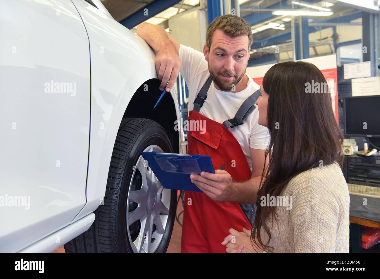 Mechaniker und Kunde sprechen in einer Werkstatt, um ein Fahrzeug zu reparieren Stockfoto