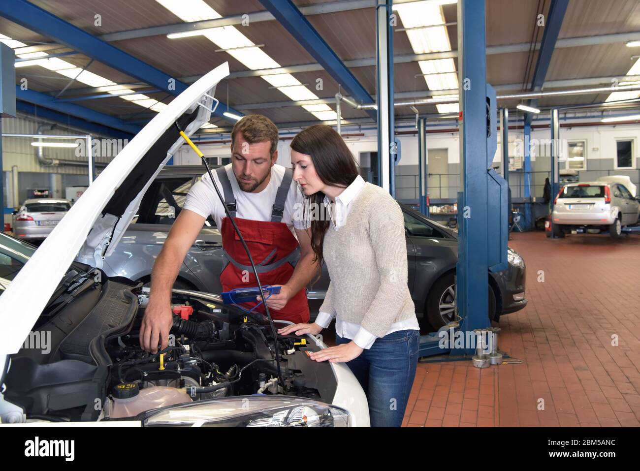 Mechaniker und Kunde sprechen in einer Werkstatt, um ein Fahrzeug zu reparieren Stockfoto