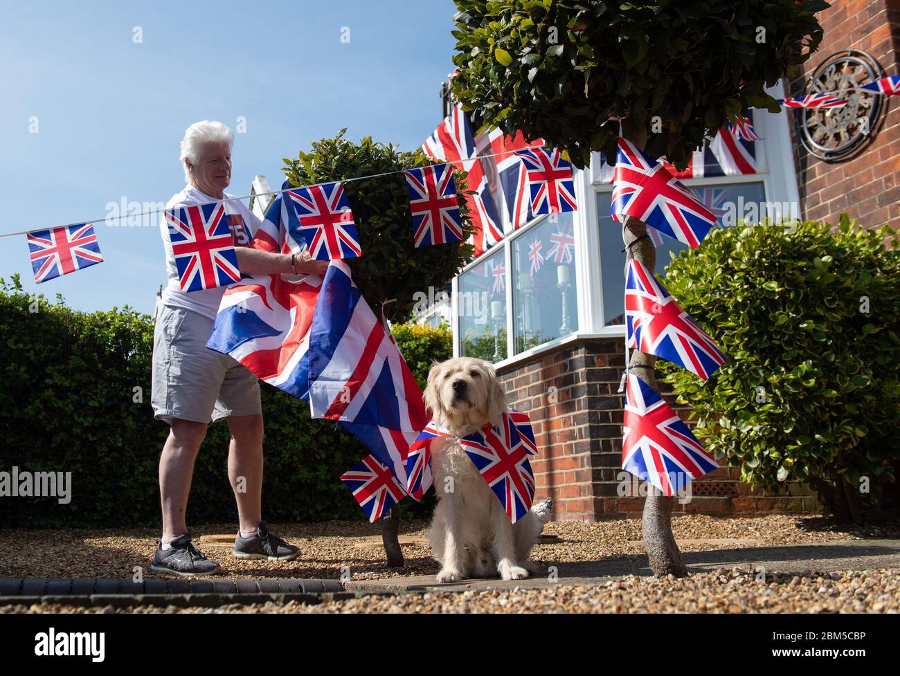Pageantmaster des VE Day 75 Bruno Peek und sein Hund Wilson, als er sein Haus in Gorleston-on-Sea, Norfolk, anlässlich des 75. Jahrestages des Endes des Zweiten Weltkriegs in Europa mit Fahnen und Apfenmalern schmückt. Stockfoto