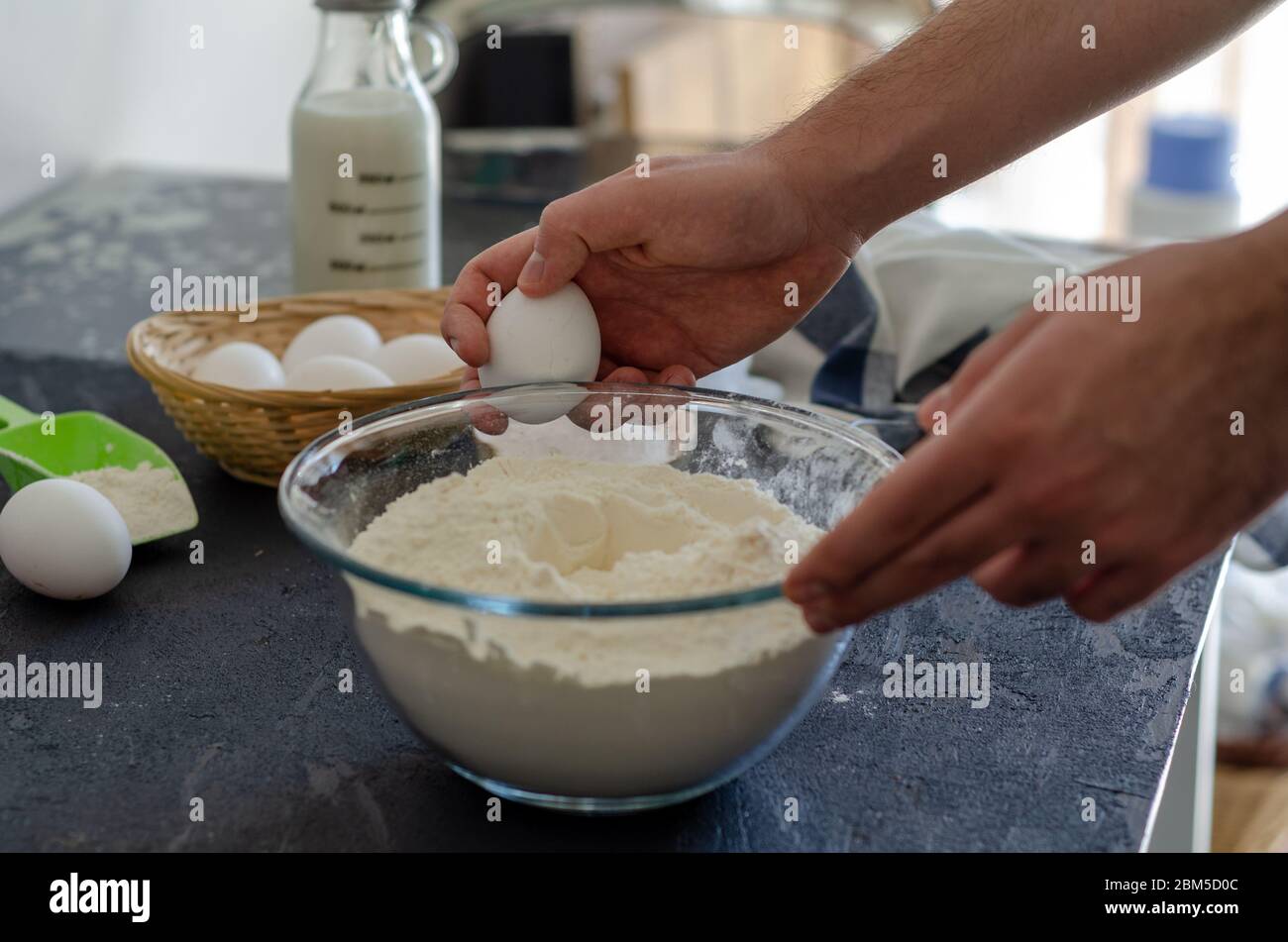 Der junge Mann bricht in der Küche Eier für Teig. Stockfoto