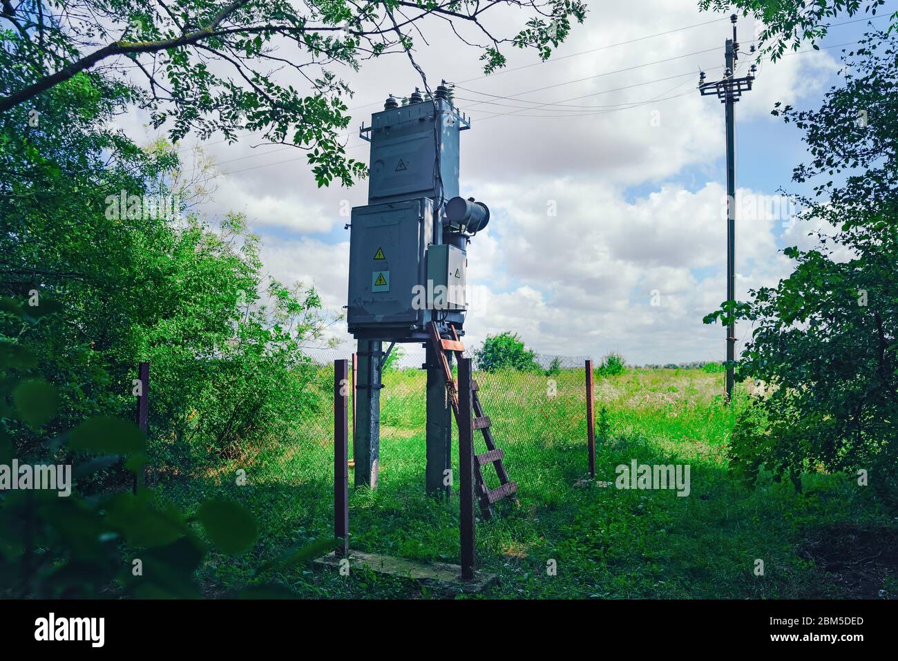 Alte funktionierende ländliche Elektroverteilertrafo im Wald. Sonniger Tag, das Konzept der Industrie. Stockfoto