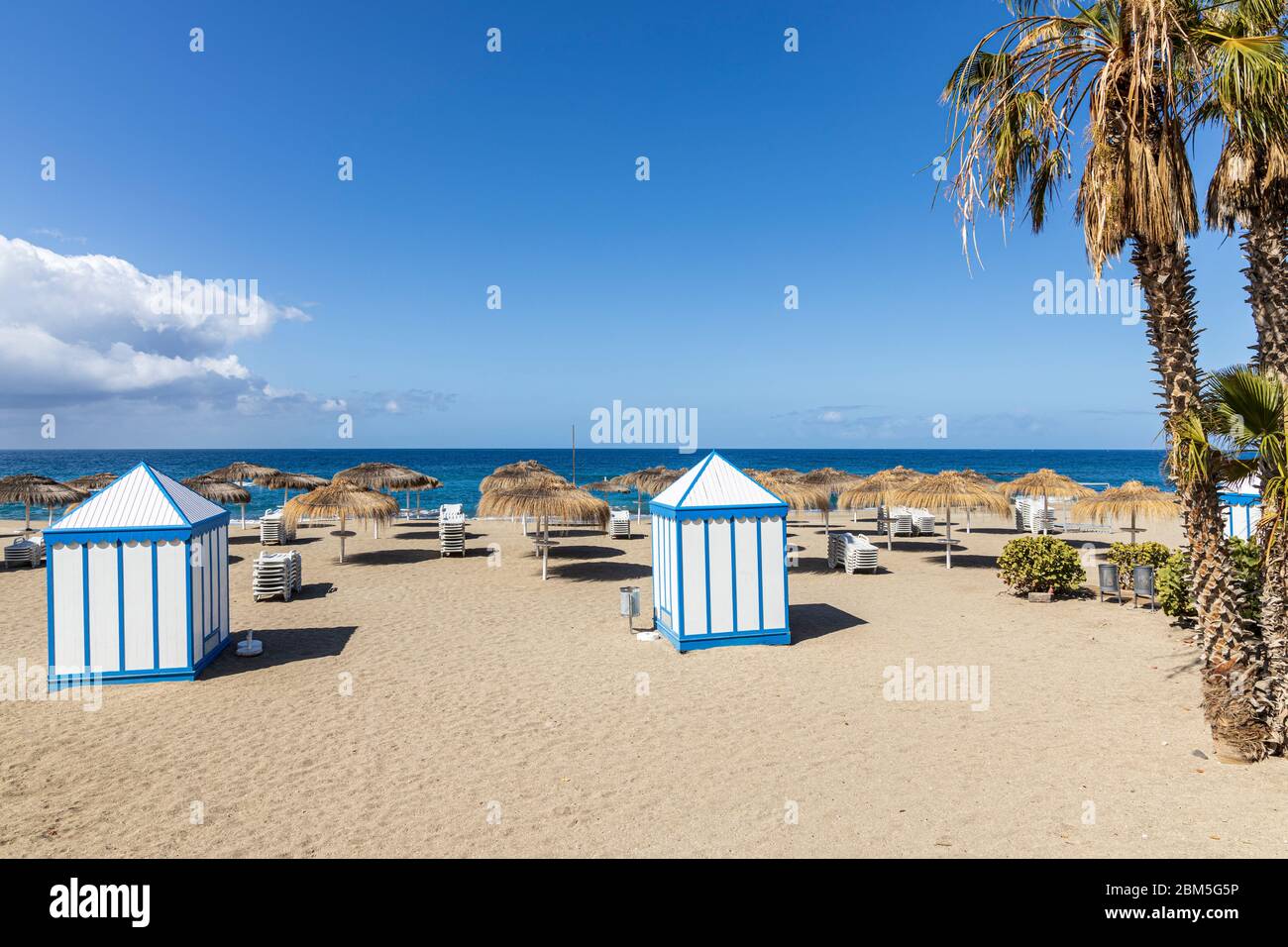 Leerer, menschenleerer Strand von Playa del Duque mit ungenutzten Sonnenschirmen und Liegen während des Notstandes von Covid 19 in Costa Adeje, Teneriffa, Kanarische Inseln Stockfoto