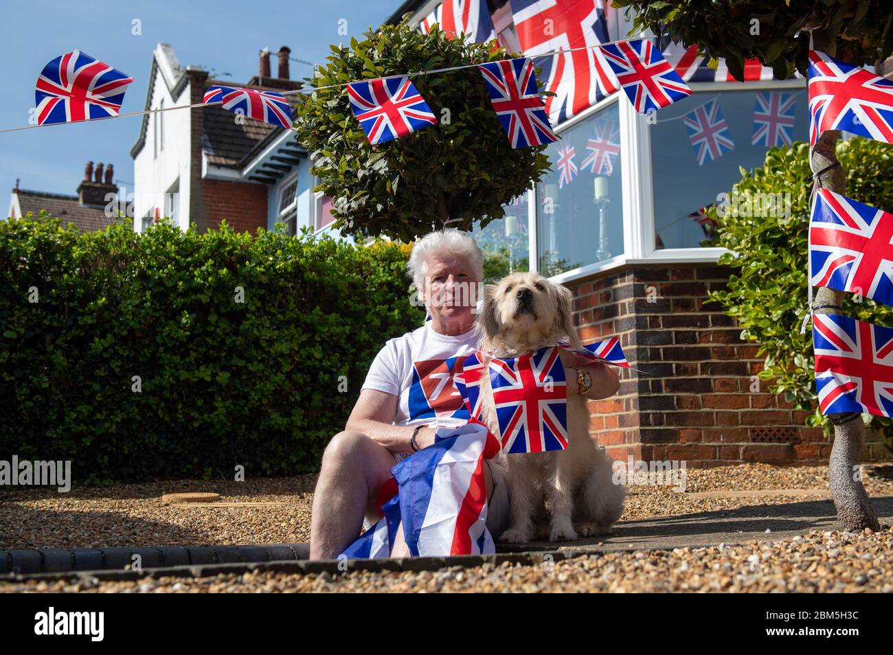 Pageantmaster des VE Day 75 Bruno Peek und sein Hund Wilson, als er sein Haus in Gorleston-on-Sea, Norfolk, anlässlich des 75. Jahrestages des Endes des Zweiten Weltkriegs in Europa mit Fahnen und Apfenmalern schmückt. Stockfoto