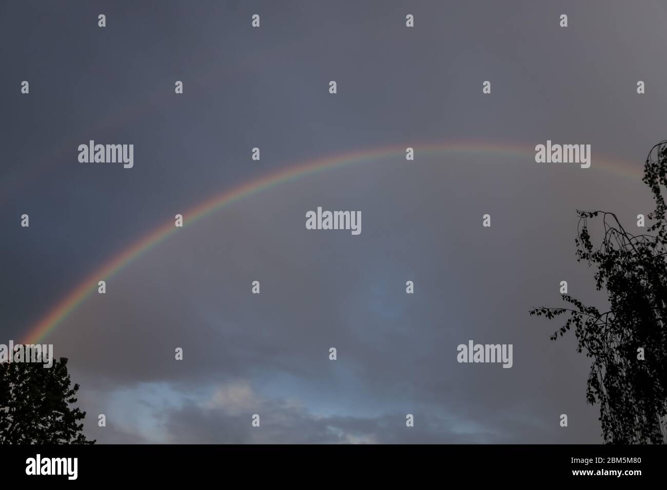 Nahaufnahme des bunten Regenbogens in stürmischem Himmel. Stockfoto