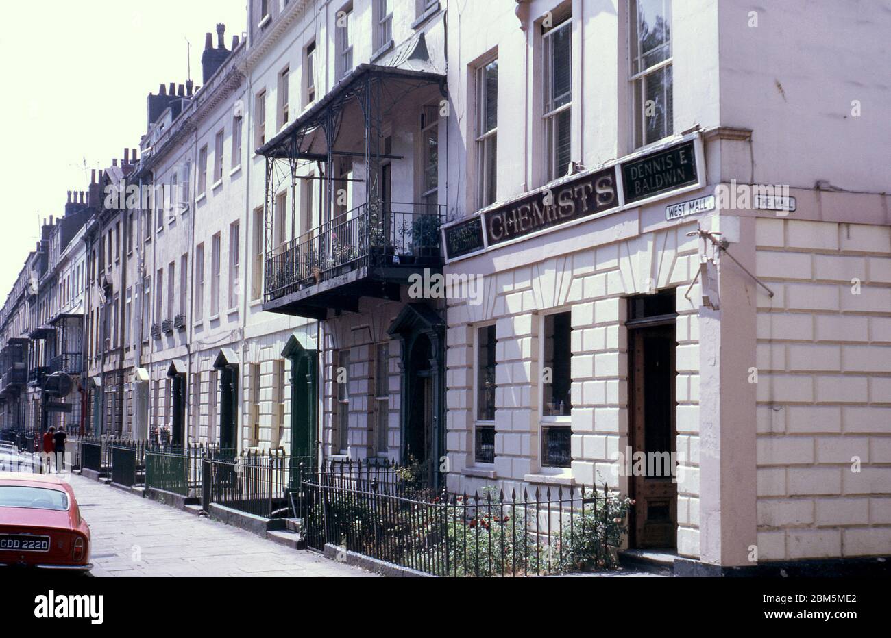 Bristol in den 60er und 70er Jahren: Die Chemiker des alten Dennis E Baldwin in der 1 West Mall, Clifton im Juni 1970. Es wurde in den 1830er Jahren gegründet und hatte hölzerne Vitrinen mit Abschnitten für die verschiedenen Zutaten, die von einem Apotheker verwendet wurden, einschließlich Tapioka und Cera alba (Bienenwachs). Dieses Foto wurde in der Nähe des Clifton Club in der Mall mit Blick auf die West Mall aufgenommen und enthält die Rückseite eines roten Aston Martin DB6. Die Gegend war beliebt bei Bristol University Studenten mit vielen Gebäuden in diesen Pre-Zentralheizung Tage in Wohnungen aufgeteilt und vermietet auf jährliche vermietet. Stockfoto