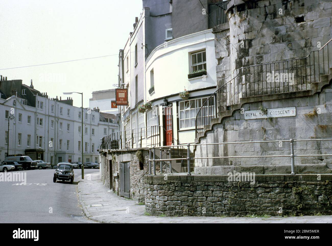Bristol in den 60er und 70er Jahren: Das südwestliche Ende des Royal York Crescent in Clifton im Juni 1970, mit Blick nach oben vorbei an Courage Portcullis Pub in Richtung der Princes Buildings auf Sion Hill, vor Parkdruck und kontrollierten Parkzonen. Die Gegend war beliebt bei Bristol University Studenten in diesen Pre-Zentralheizung Tage mit vielen Gebäuden in Wohnungen aufgeteilt und vermietet auf jährliche vermietet. Stockfoto