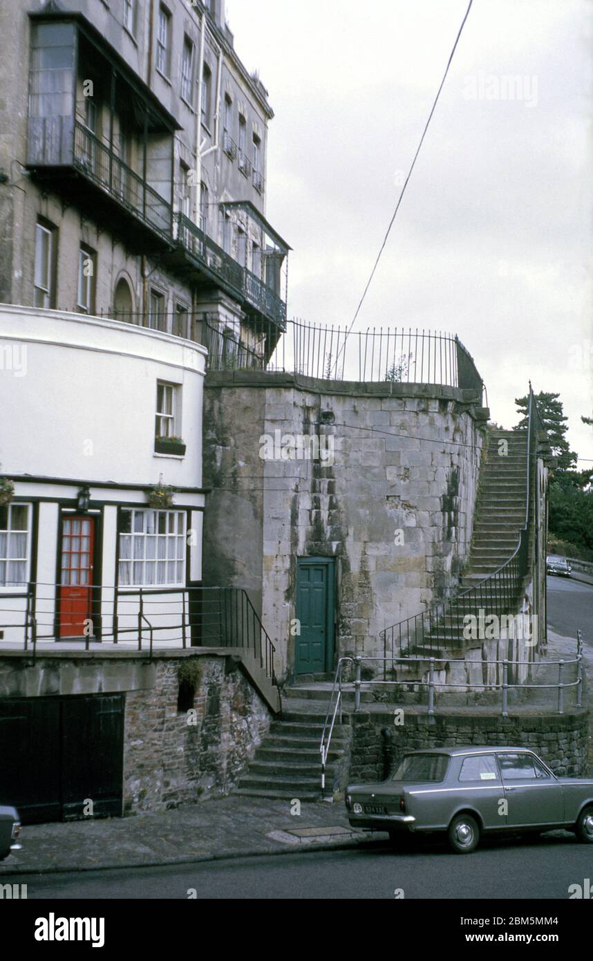 Bristol in den 60er und 70er Jahren: Das südwestliche Ende des Royal York Crescent, eine denkmalgeschützte spätgeorgianische Terrasse in Clifton, neben der Ecke des Portcullis Pub auf Sion Hill im Juli 1970. Die Gegend war beliebt bei Studenten der Universität Bristol in jenen Tagen vor der Zentralheizung mit vielen Gebäuden in Wohnungen aufgeteilt und vermietet auf jährliche Vermietungen, darunter einige der maroden Gebäude in der Crescent, wo mehrere Balkone waren in schlechtem Zustand. Stockfoto