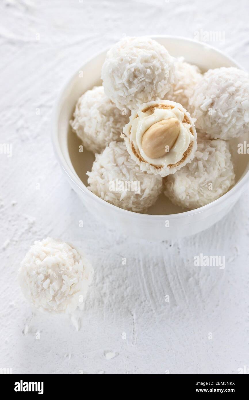 Bonbons mit Nougat und Mandeln in Kokosflocken auf hellem Hintergrund Stockfoto