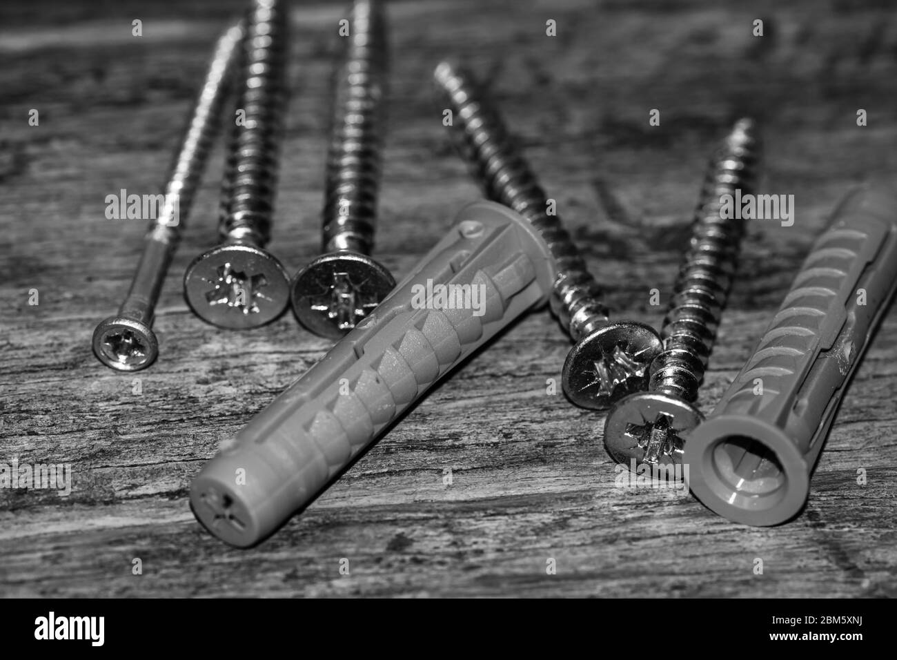 Nahaufnahme Foto von Schrauben, Satz von Schrauben in einer Konstruktion Abstraktion. Industrieller Hintergrund mit Schrauben auf einer Holzplatte. Stockfoto