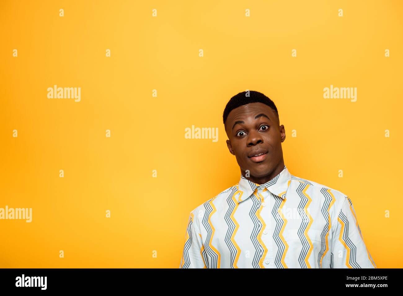 Überrascht afroamerikanischen Mann mit prall Augen isoliert auf gelb Stockfoto