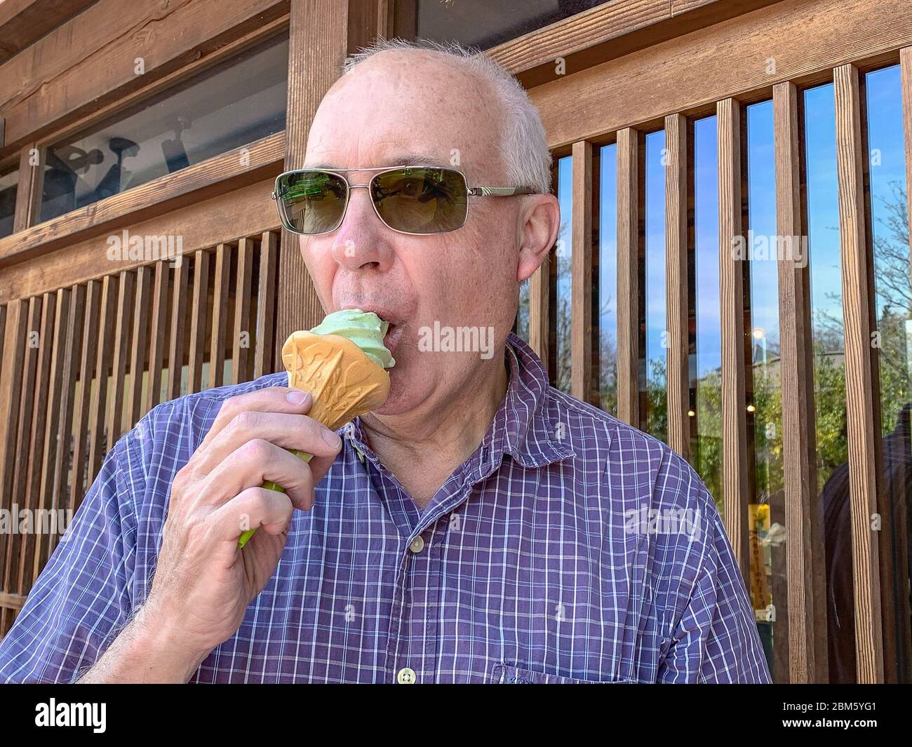 Causasian Mann trägt Sonnenbrille essen grünes Eis in einem Kegel Stockfoto