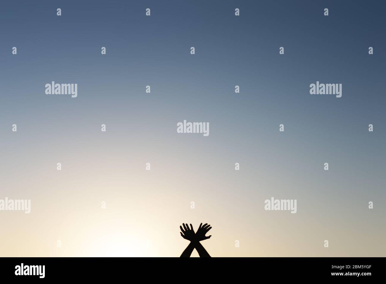 Arme und Hände des Mannes, die am unteren Rand des Fotos gegen den Himmel gekreuzt sind. Geben Sie eine minimale Bearbeitung Stockfoto