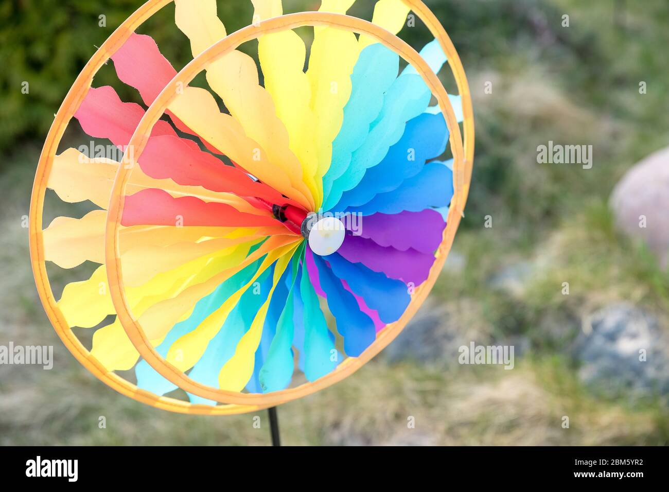 Bunte Windrad Spinnen im Wind vor einem natürlichen grünen Hintergrund.Fokus auf der Mitte des Windrads.Bunte Spielzeug. Freiheit und lustige Konzept.Spielzeug Stockfoto