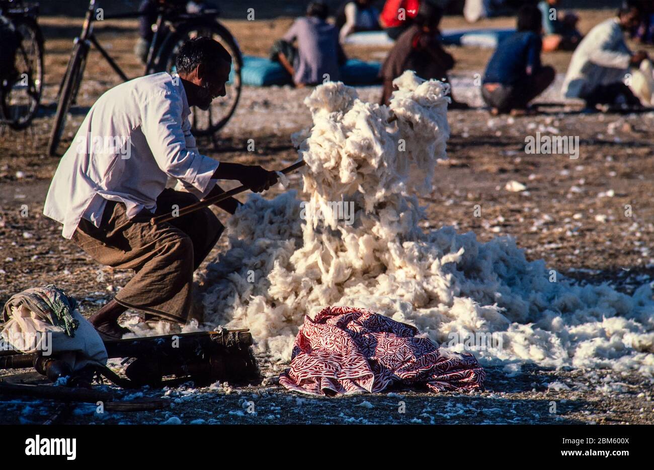 Kathmandu, Nepal - Nov 1986: Ein Mann, der Wollfleece für den Verkauf auf dem Wollmarkt in einem Park in Kathmandu, Nepal, aufflupft. 35-mm-Film gescannt. Stockfoto