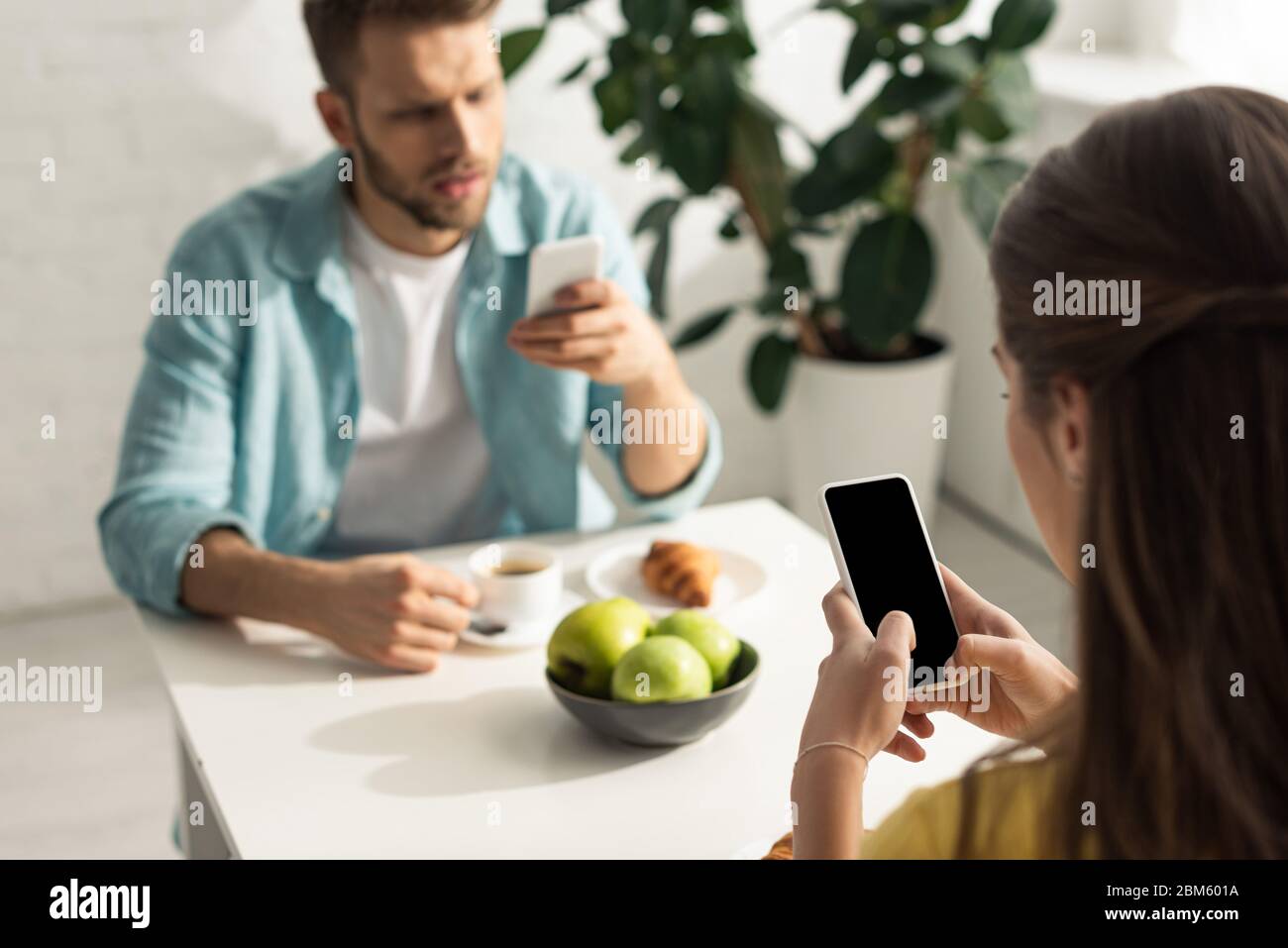 Selektiver Fokus der Frau mit Smartphone in der Nähe Freund beim Frühstück chatten Stockfoto