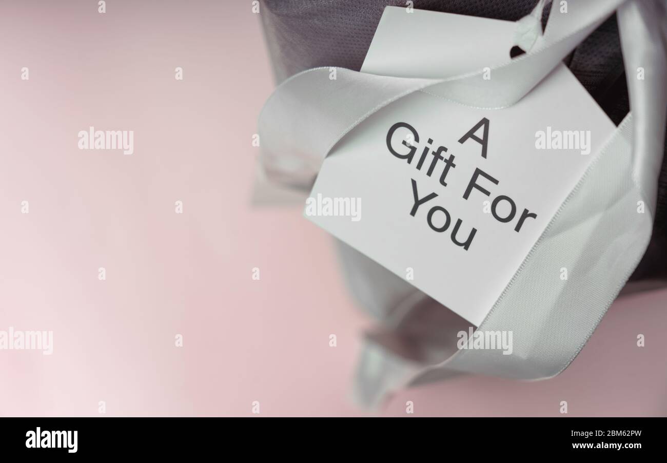 Karte auf Geschenkbox mit Text : EIN Geschenk für Sie auf rosa Hintergrund mit Kopierraum Stockfoto