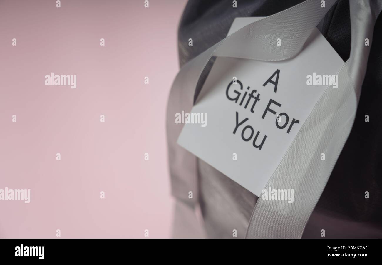 Karte auf Geschenkbox mit Text : EIN Geschenk für Sie auf rosa Hintergrund mit Kopierraum Stockfoto