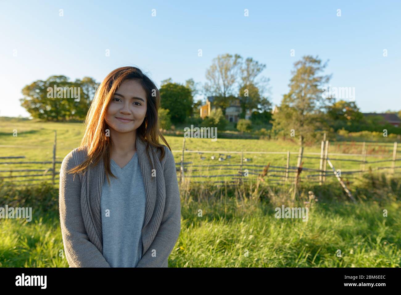 Junge schöne asiatische Frau in ruhigen grasbewachsenen Ebene mit der Natur Stockfoto