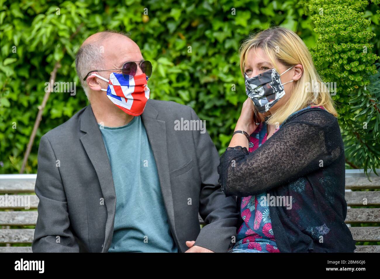 Steve und Elaine Watson aus dem Dorf Croscombe, in der Nähe von Wells, tragen chirurgische Gesichtsmasken, die mit Cinegirl-Drucken bedeckt sind, und eine Union-Flagge des Künstlers Shelley Dyer-Gibbins, Die Designer Gesichtsmasken für alle 600 Bewohner des Dorfes Somerset aus medizinischem Maskenmaterial und einigen ihrer Kunstdruckmaterialien hergestellt hat, die sie hinterlassen hatte. Stockfoto