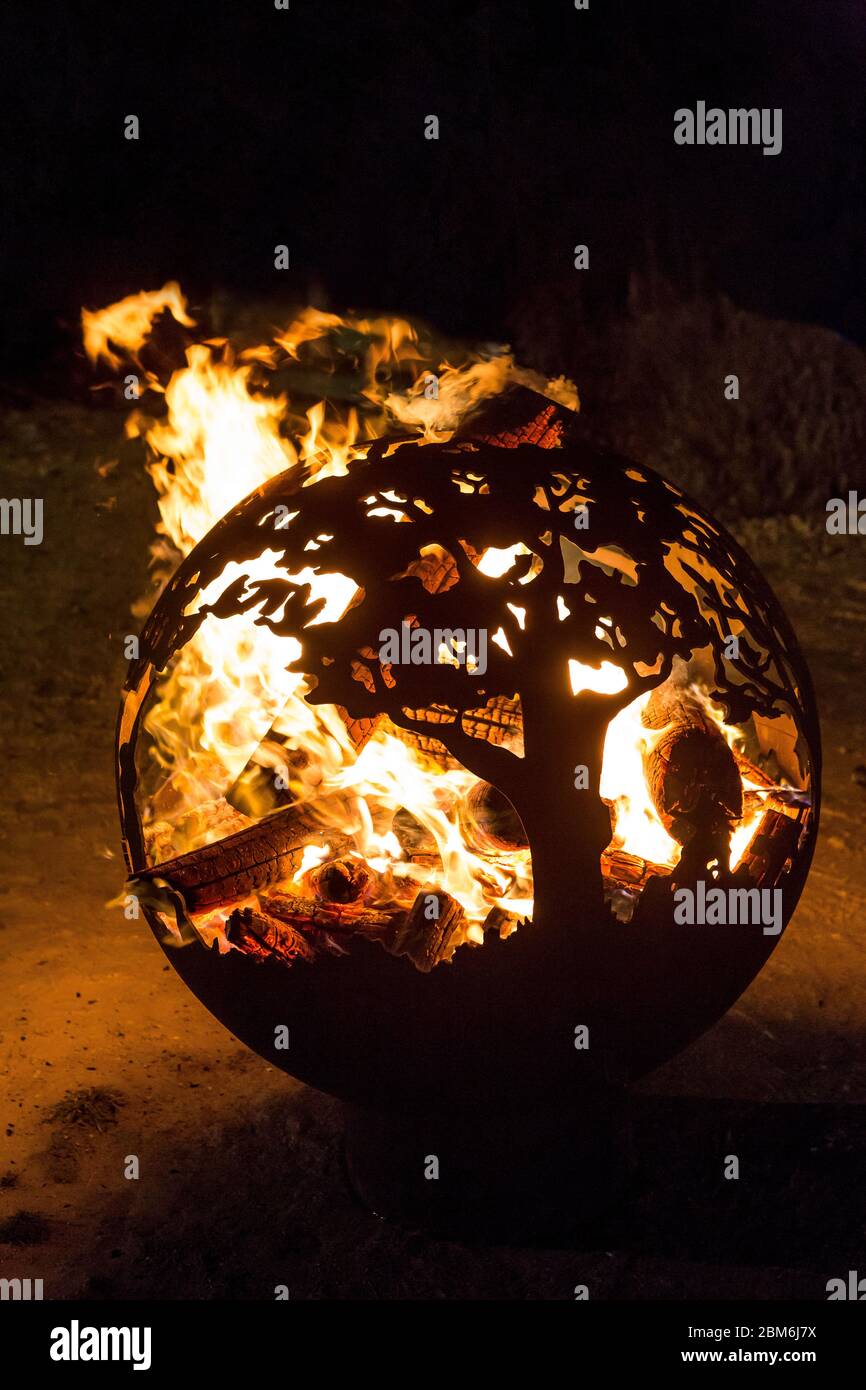 Bringt das Innere heraus mit wunderschön gearbeiteter kugelförmiger Feuerball-Feuerkugel aus Stahl mit riesigen Flammen in einem Garten in Kent bei Nacht. Stockfoto