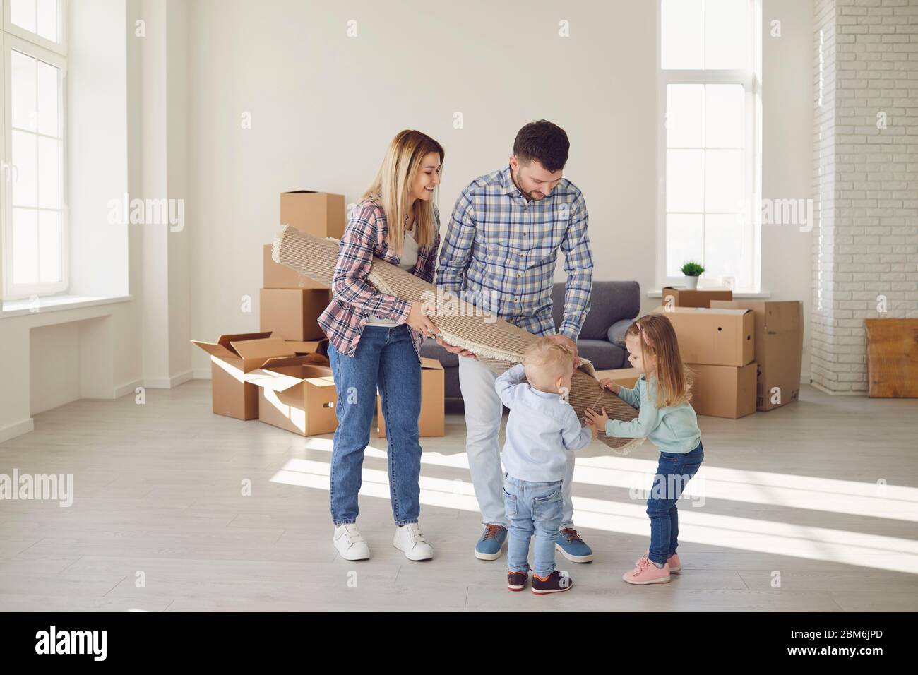 Glückliche Familie mit Teppich auf dem Boden in einer neuen Wohnung. Stockfoto