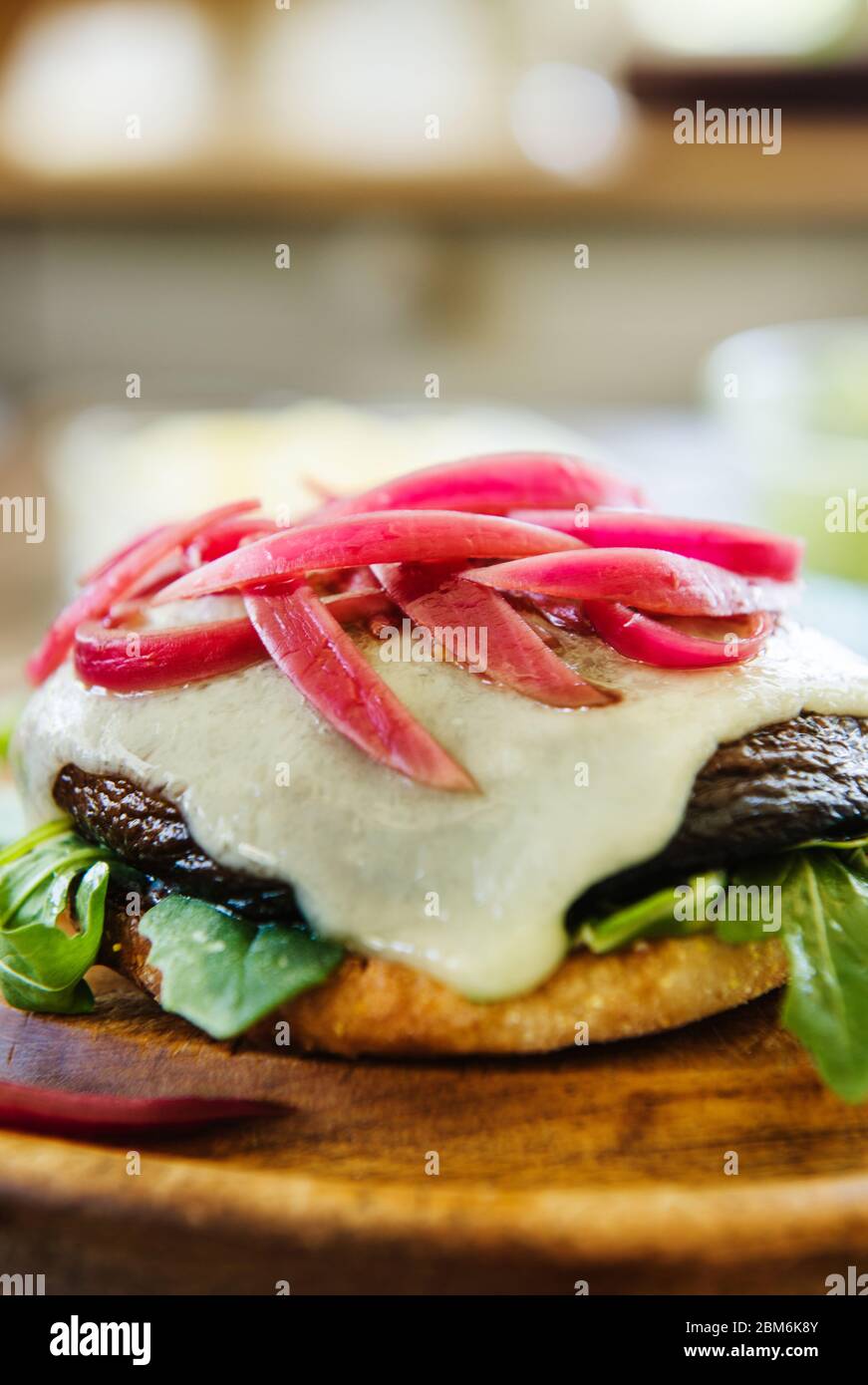 Portabella Pilz-Sandwich mit Havarti Käse, roten Zwiebeln, Rucola und Guacamole auf einem englischen Muffin-Brötchen Stockfoto
