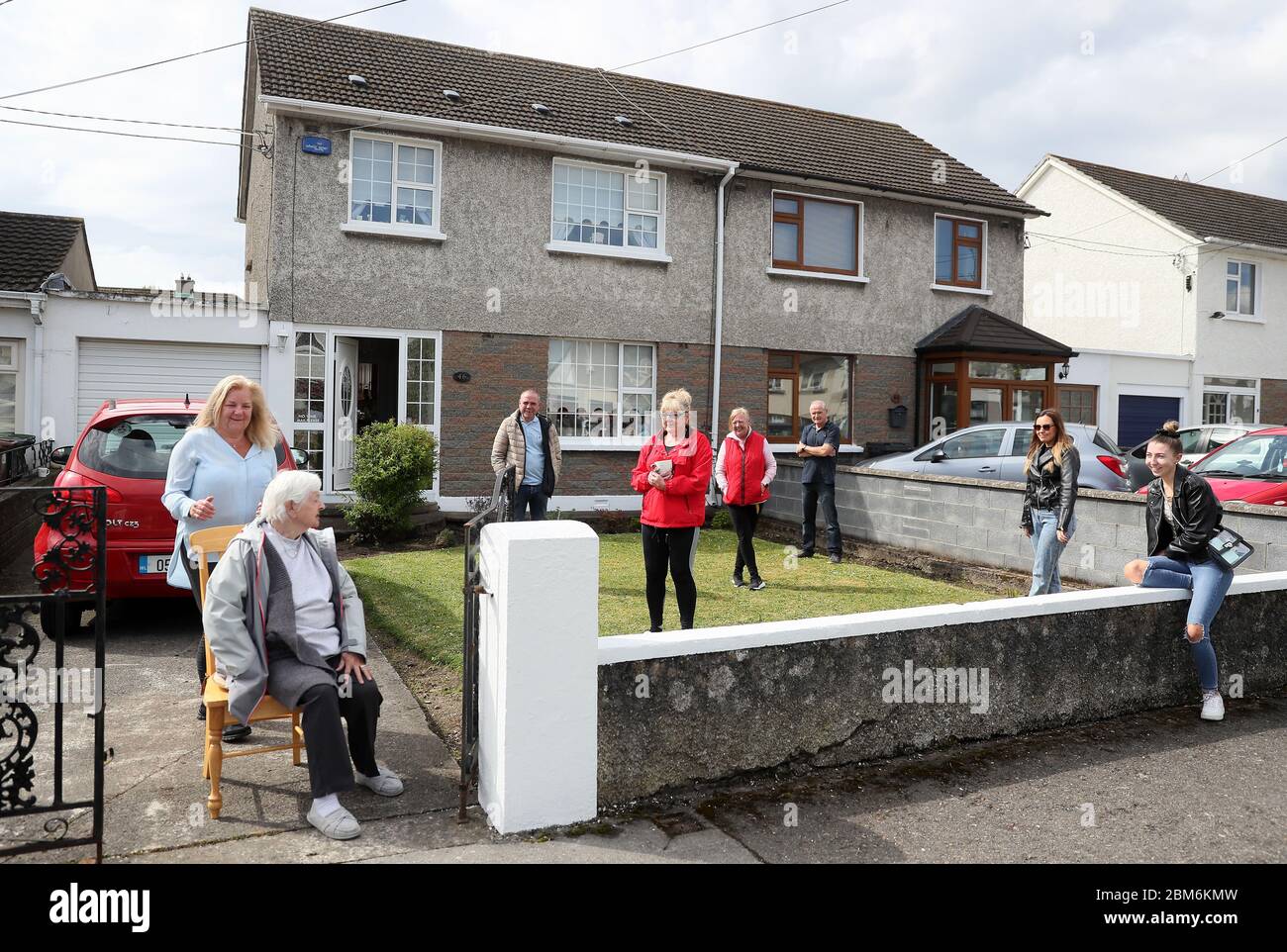 Hannah Powell (sitzend), Nachbar des verstorbenen Frank McDonald, Mit Familienangehörigen außerhalb ihres Hauses in Dublin als Nachbarn versammelten sich, um ihre Achtung zu zahlen, um die langjährige Bewohner von Grove Park Avenue als seine Beerdigung Cortege machte es weit die Straße, die er lebte auf für über 60 Jahre. Bilddatum: Donnerstag, 7. Mai 2020. Siehe PA Geschichte GESUNDHEIT Coronavirus Irland. Das Foto sollte lauten: Brian Lawless/PA Wire Stockfoto