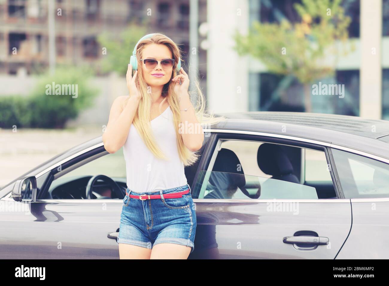 Junge moderne Frau mit Spaß Musik auf Kopfhörer in der Stadt zu hören Stockfoto
